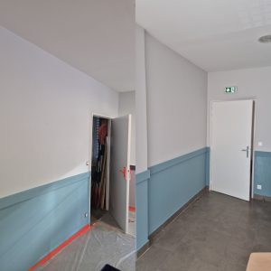Couloir intérieur en rénovation, avec une porte de rangement ouverte et un panneau de sortie de secours
